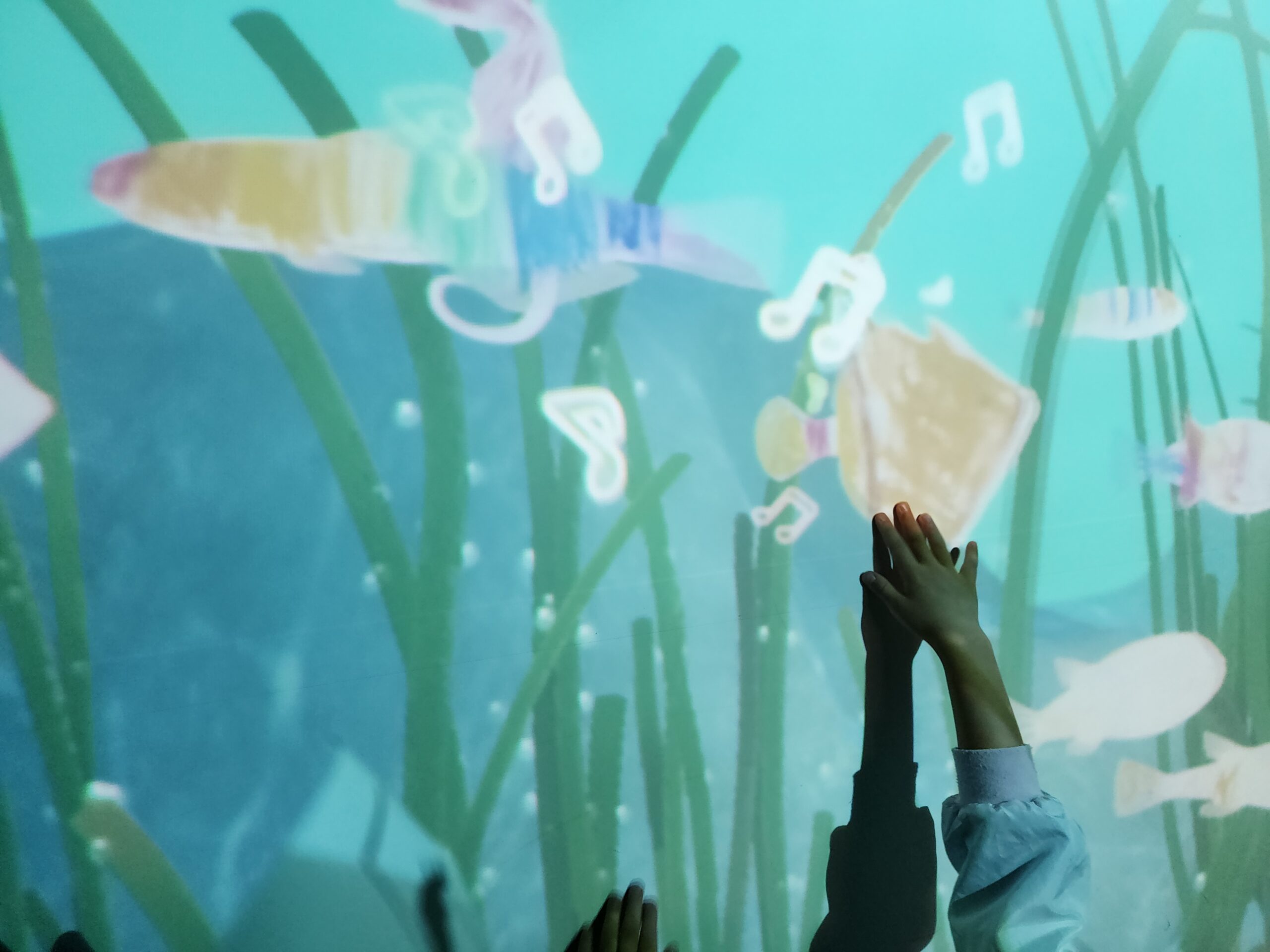 壁一面に映し出され泳ぎ出す、自分で塗った魚たち